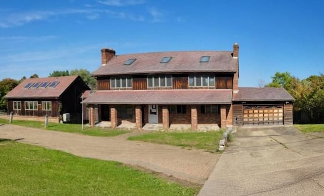 view of front of house with driveway, an attached garage, a chimney, and a front yard