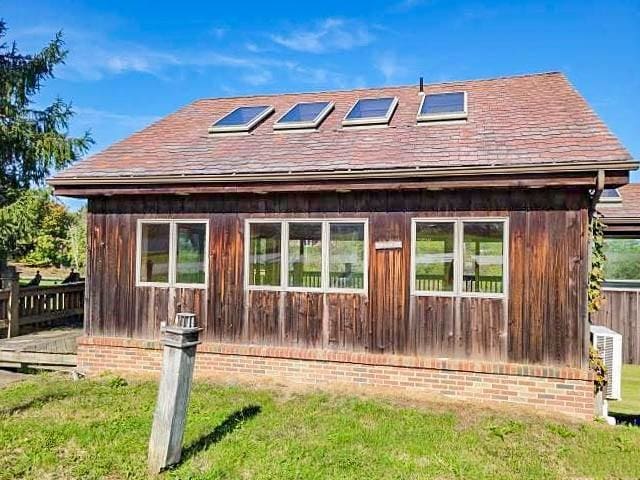back of property with roof with shingles and a yard