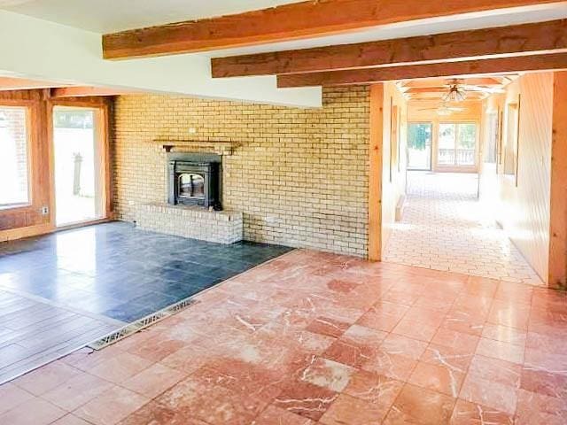 unfurnished living room featuring brick wall, beamed ceiling, and ceiling fan