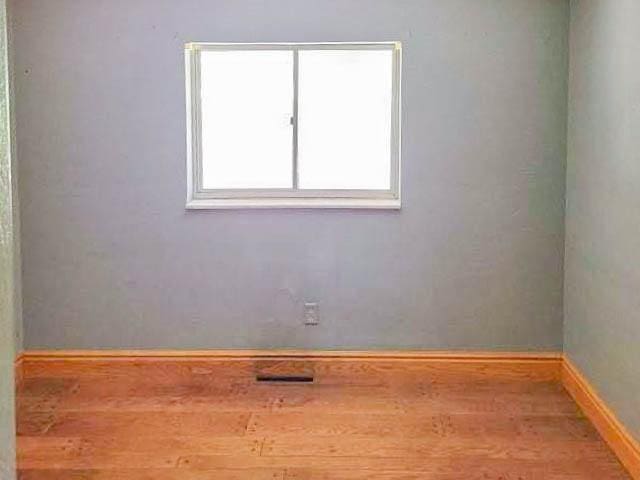 unfurnished room with wood finished floors and baseboards
