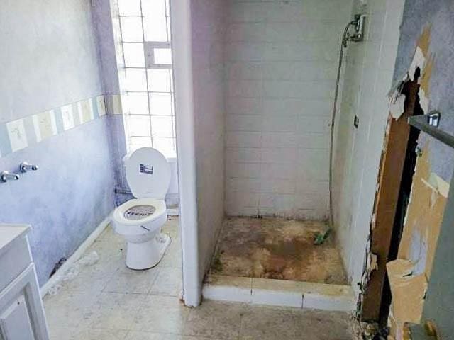 bathroom featuring toilet, a tile shower, and vanity