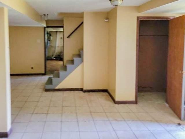 corridor featuring stairway, light tile patterned floors, and baseboards