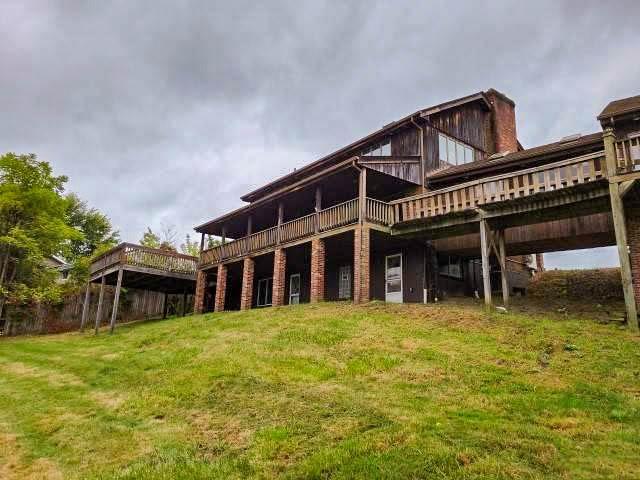 back of property with a deck, a yard, and a chimney