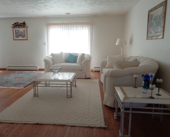 living room featuring a baseboard heating unit, hardwood / wood-style floors, and a textured ceiling