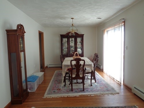 dining area with light wood-type flooring, baseboard heating, and a notable chandelier