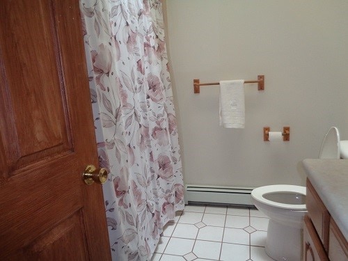 bathroom featuring a shower with curtain, vanity, tile patterned flooring, toilet, and baseboard heating