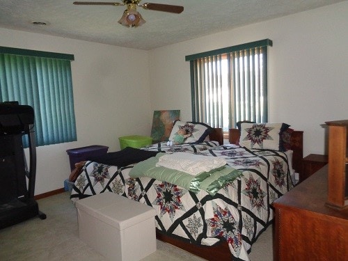 bedroom with a textured ceiling, light colored carpet, and ceiling fan