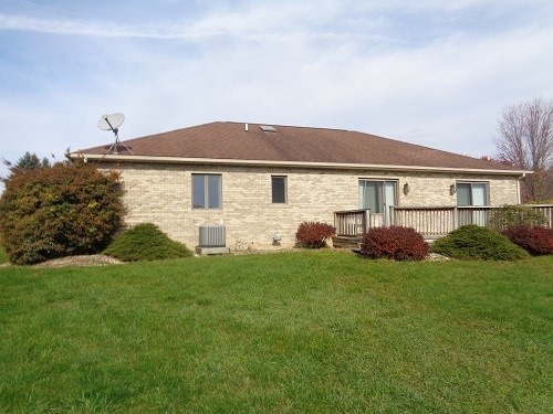 back of house with central AC unit and a lawn