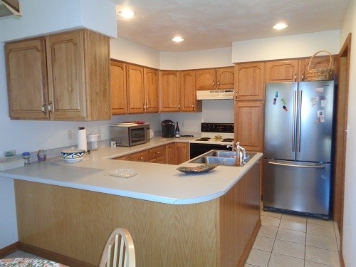 kitchen with kitchen peninsula, light tile patterned floors, and stainless steel appliances