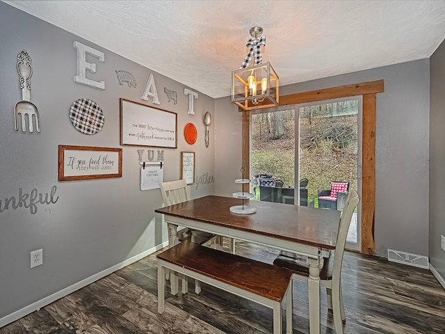 dining room with a textured ceiling, dark hardwood / wood-style floors, and an inviting chandelier