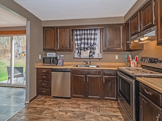 kitchen featuring wood counters, dark brown cabinets, stainless steel appliances, and sink