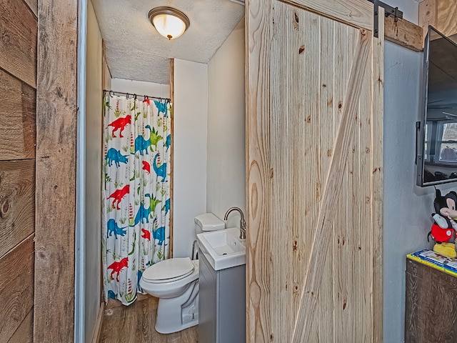 bathroom with curtained shower, a textured ceiling, toilet, vanity, and hardwood / wood-style flooring