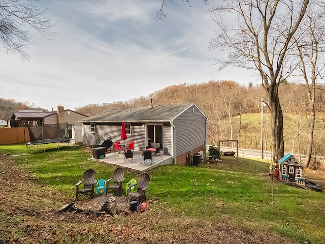 rear view of house featuring a trampoline, a patio, a yard, and central air condition unit