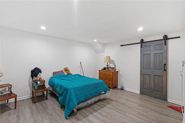 bedroom with light wood-type flooring and a barn door