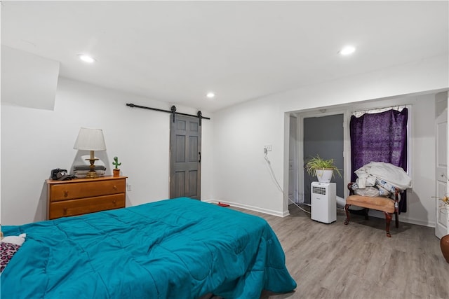 bedroom featuring a barn door and light hardwood / wood-style flooring