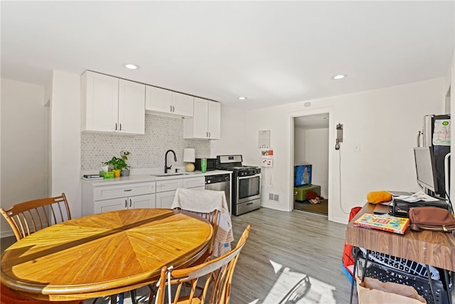 kitchen featuring stainless steel appliances, white cabinetry, sink, backsplash, and light wood-type flooring