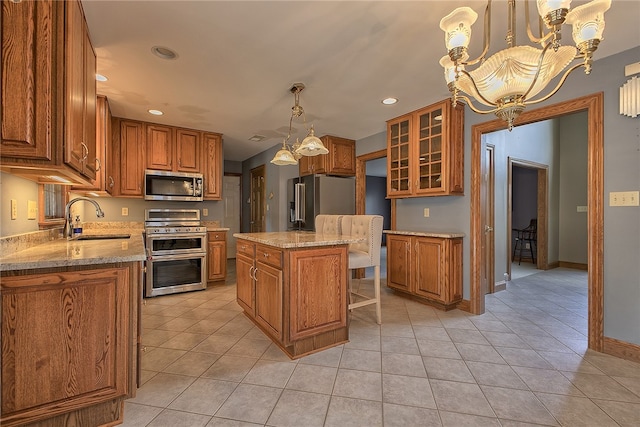 kitchen with stainless steel appliances, a center island, hanging light fixtures, sink, and light tile patterned flooring