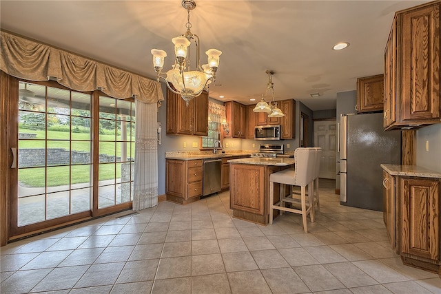 kitchen featuring stainless steel appliances, a kitchen island, light tile patterned floors, light stone countertops, and pendant lighting