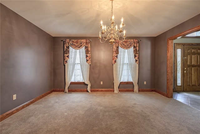 carpeted empty room featuring a notable chandelier