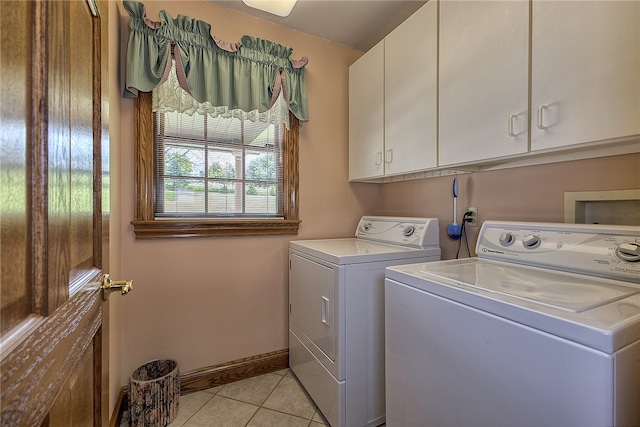 clothes washing area with washer and clothes dryer, cabinets, and light tile patterned floors