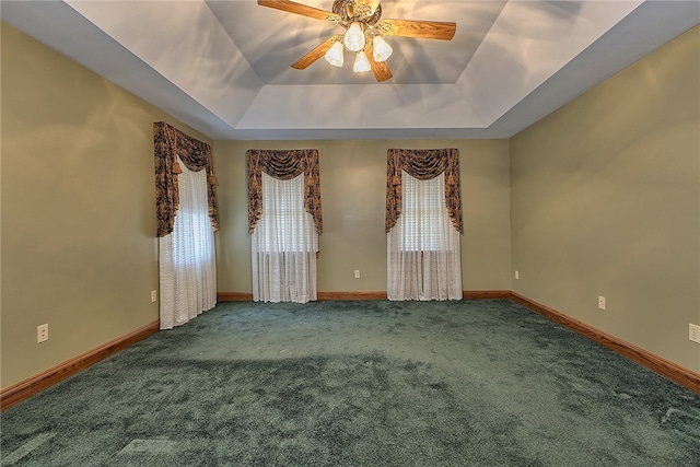 empty room featuring carpet, a wealth of natural light, ceiling fan, and a tray ceiling