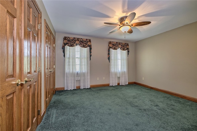 spare room with ceiling fan and dark carpet