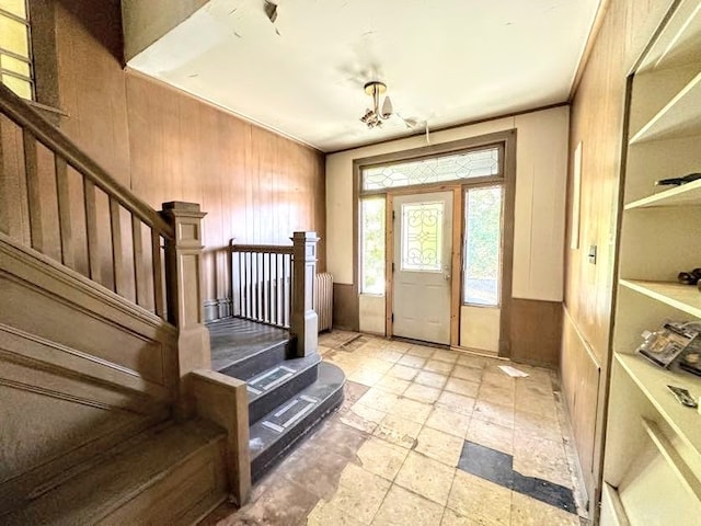 foyer entrance featuring radiator and wooden walls