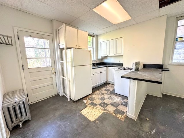 kitchen with radiator, a paneled ceiling, white cabinetry, sink, and white appliances