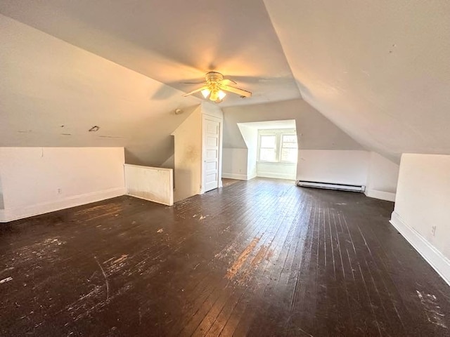 additional living space featuring dark wood-type flooring, ceiling fan, baseboard heating, and vaulted ceiling