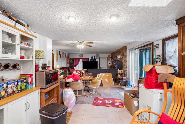 interior space featuring a textured ceiling, light tile patterned floors, and ceiling fan