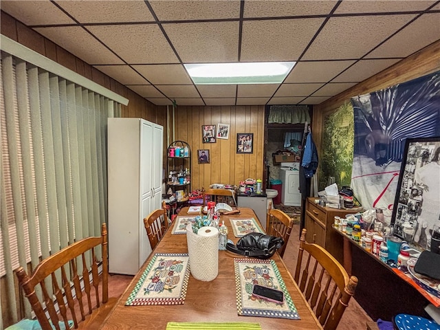 dining area with a paneled ceiling and wooden walls