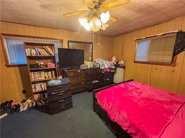 carpeted bedroom with wood walls and ceiling fan