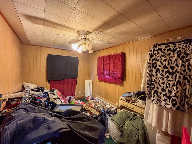 bedroom featuring a baseboard radiator, wooden walls, and ceiling fan