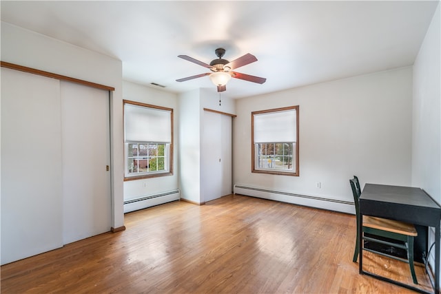 unfurnished office with light wood-type flooring, ceiling fan, and a baseboard radiator