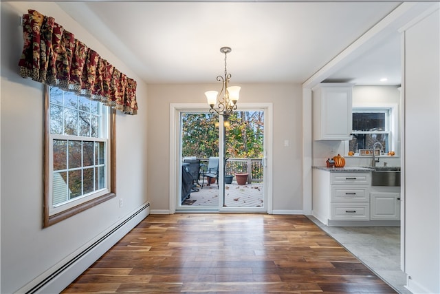 unfurnished dining area featuring dark wood-type flooring, baseboard heating, a healthy amount of sunlight, and sink