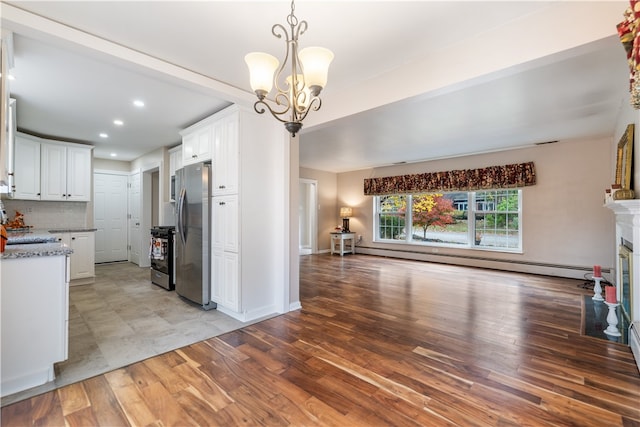 kitchen with stainless steel appliances, white cabinets, a baseboard radiator, and tasteful backsplash