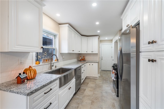 kitchen featuring stainless steel appliances, sink, light stone counters, tasteful backsplash, and white cabinets