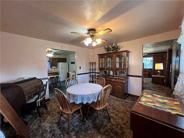 dining room with a textured ceiling, dark colored carpet, and ceiling fan