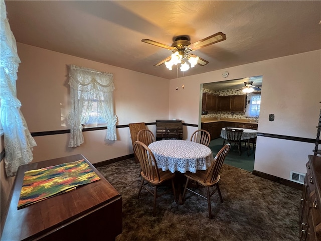 dining room featuring ceiling fan and dark colored carpet