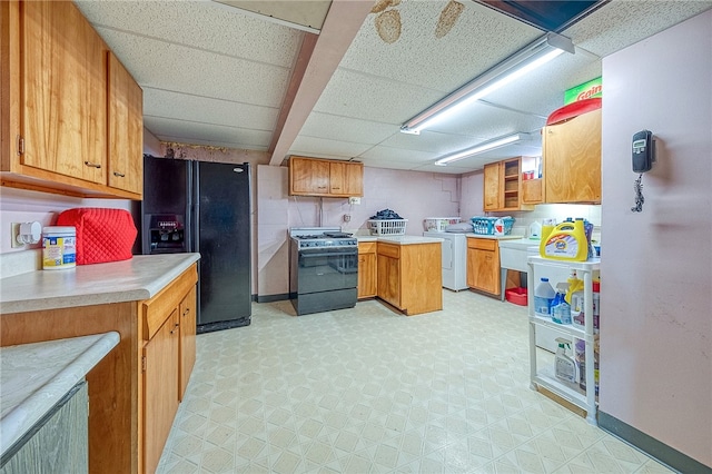 kitchen featuring a drop ceiling, washer / clothes dryer, and black appliances