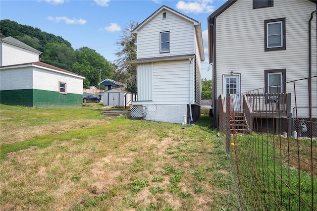 back of property with a shed, a lawn, and a deck