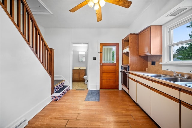 kitchen with sink, ornamental molding, ceiling fan, light hardwood / wood-style flooring, and stainless steel oven