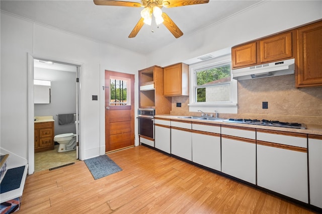 kitchen with stainless steel gas cooktop, oven, tasteful backsplash, crown molding, and light wood-type flooring