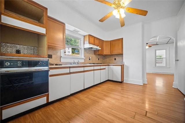 kitchen with decorative backsplash, oven, ornamental molding, baseboard heating, and light wood-type flooring