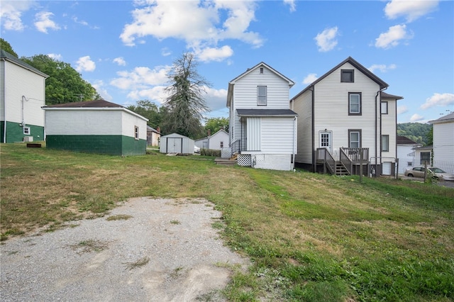 rear view of property featuring a storage shed and a yard