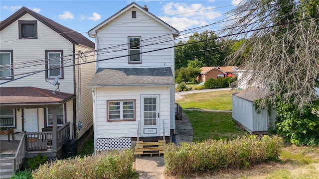 back of property with a lawn and a storage shed