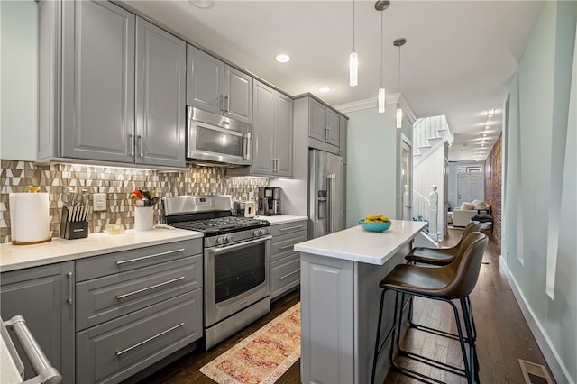 kitchen featuring stainless steel appliances, backsplash, crown molding, dark wood-type flooring, and gray cabinets