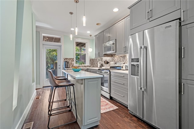 kitchen featuring dark wood-type flooring, gray cabinetry, appliances with stainless steel finishes, and a center island