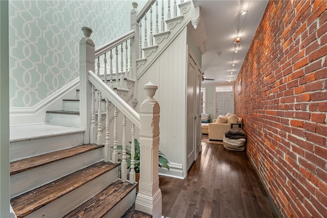 stairway featuring hardwood / wood-style flooring and brick wall