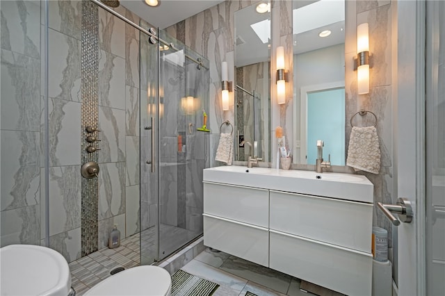 bathroom featuring a shower with door, vanity, toilet, and tile walls